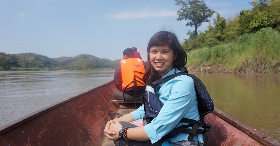 Erin is pictured smiling on a boat in a river. 