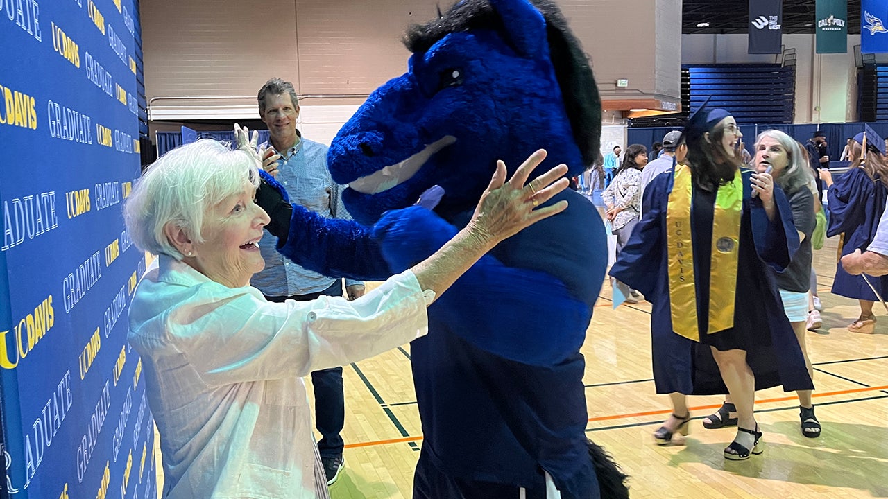 School mascot Gunrock dances with a woman as other look on.
