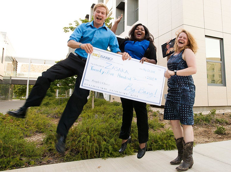 Three people holding a big check