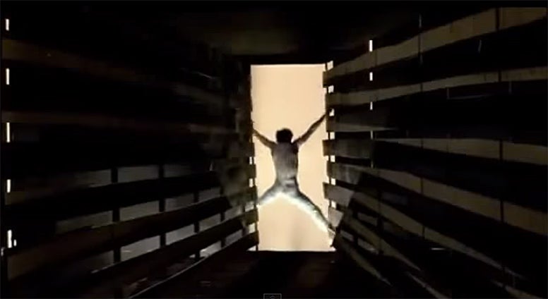 A man leaping out from a long hallway in a warehouse