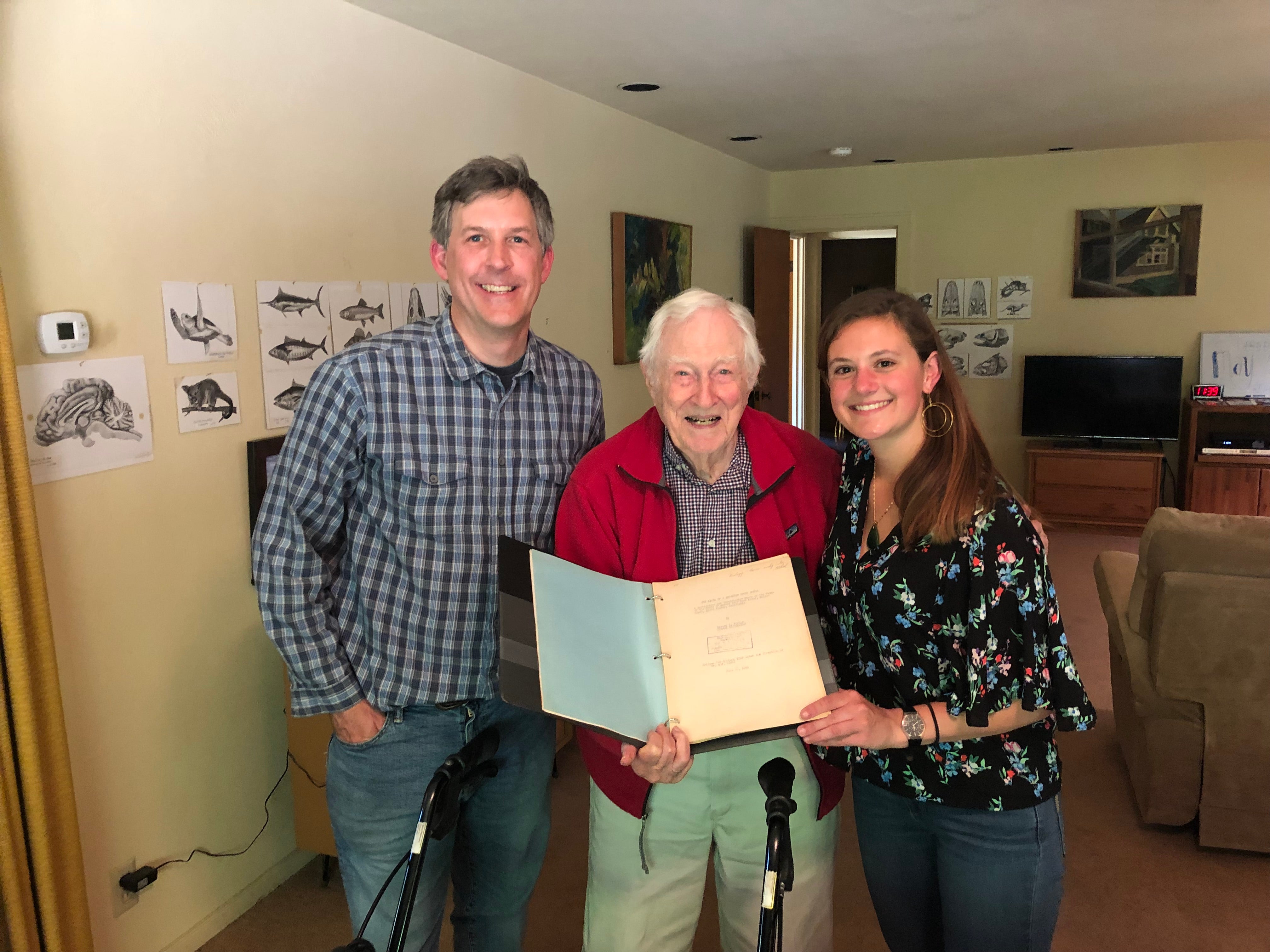 Eric Sanford, Milton Hildebrande and Emily Longman smile at camera holding 1941 mussel bed manuscript