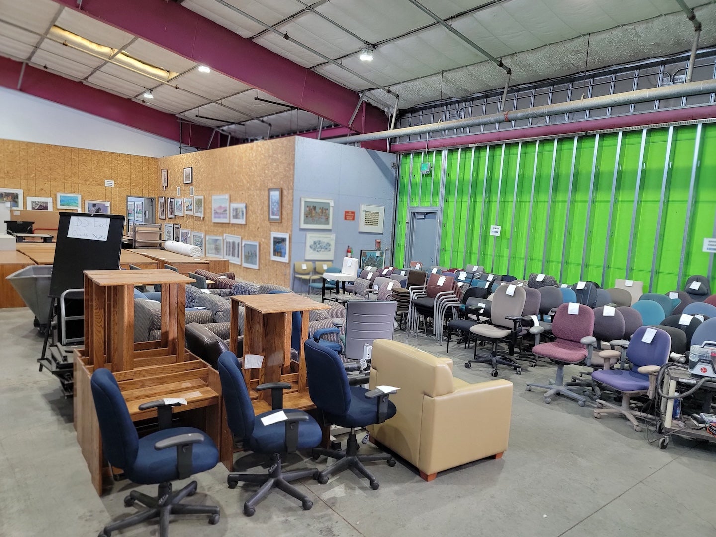 Rows of office chairs, desks and drawers are lined up inside the AggieSurplus building.