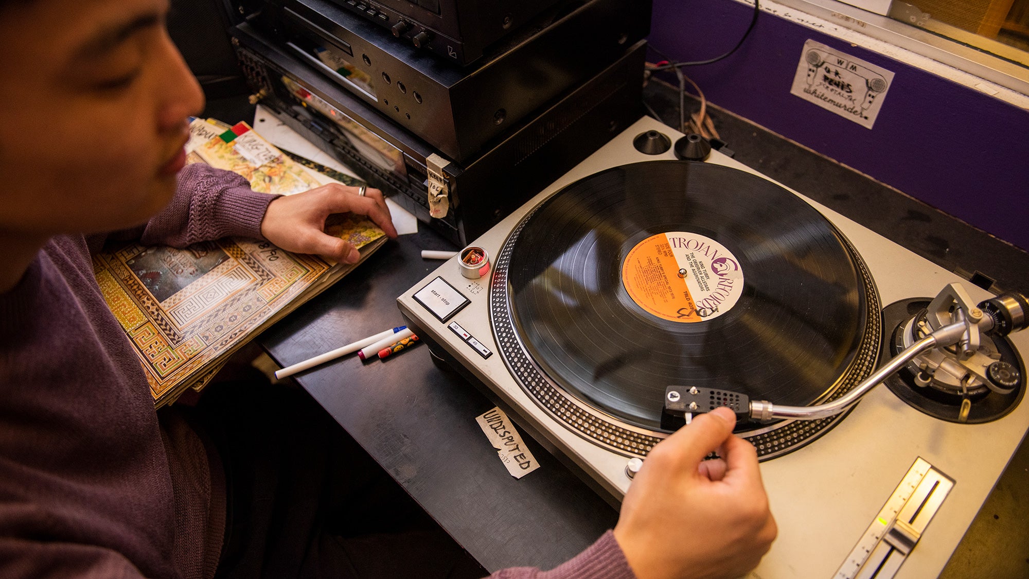 Student plays a record on a turntable in a dimly lit room