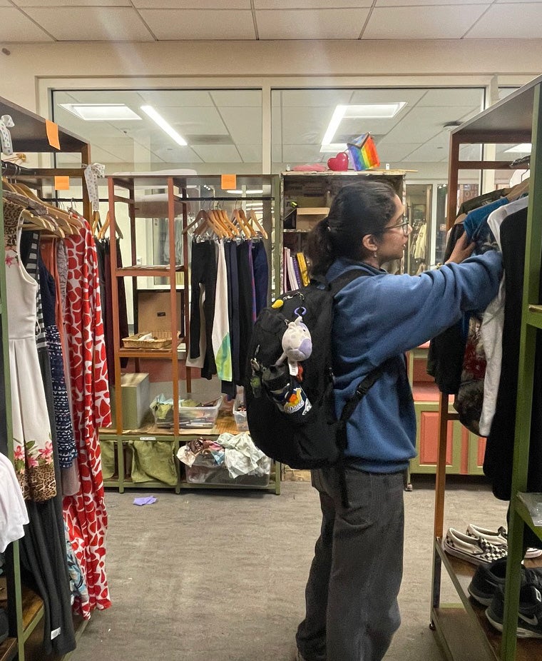 Student sorts through clothing on a rack inside a store.