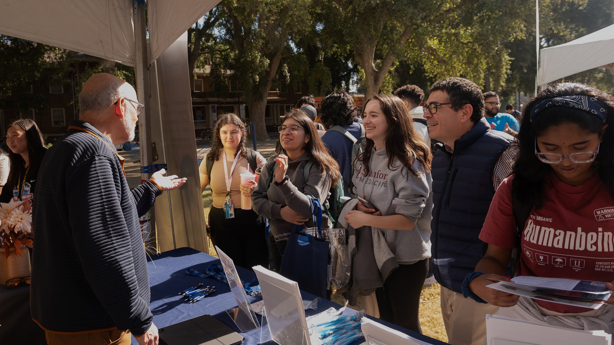 Three undergraduates in "Becoming a Latino Scientist," from the left Kaitlyn Menjivar-Esquivel, Itzel Gonzalez and Peyton Apruzzese, learn about opportunities at the Graduate and Law School Fair on the Quad Oct. 23 for an assignment given by instructor Luis Carvajal-Carmona, (center), a professor of biochemistry and molecular medicine who oversees campuswide Avanza HSI initiatives as associate vice chancellor for academic diversity in Diversity, Equity and Inclusion. They are talking with Brad Pollock, in the booth, chair of the Department of Public Health Sciences in the School of Medicine. (Gregory Urquiaga/UC Davis)