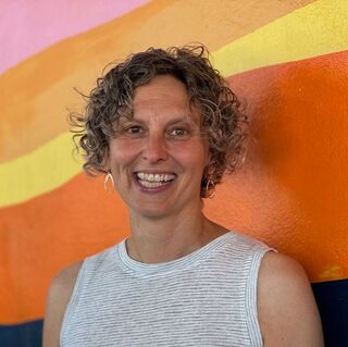 Woman in white top in front of rainbow-colored background