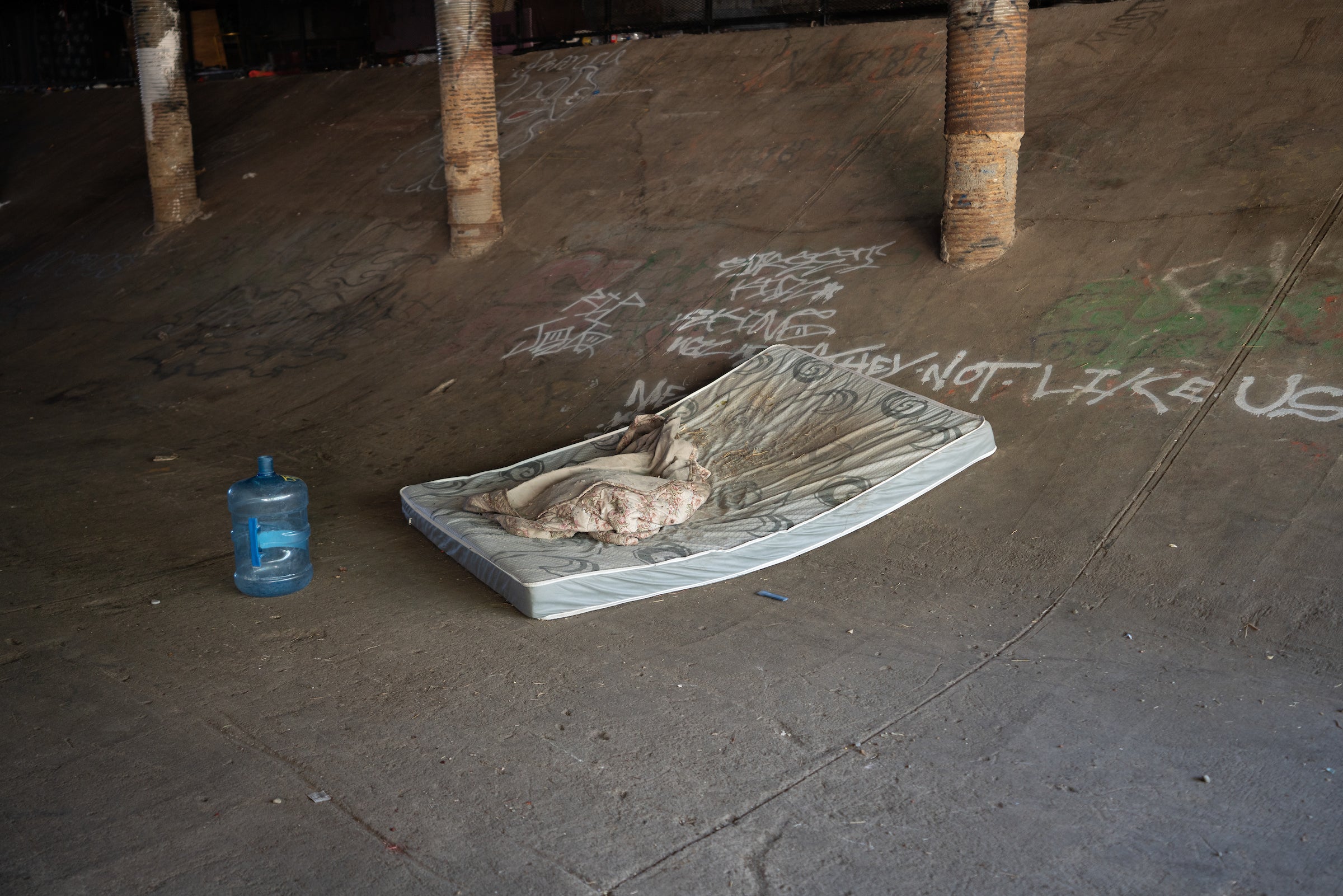 used mattress sits on concrete floor of underpass tunnel