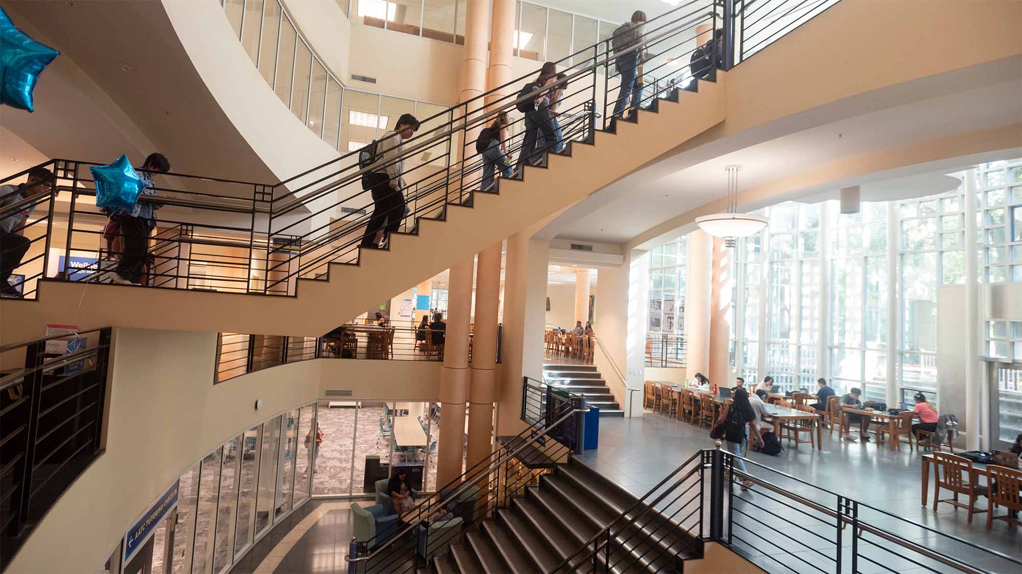 People walk up and down stairs inside Shields Library.