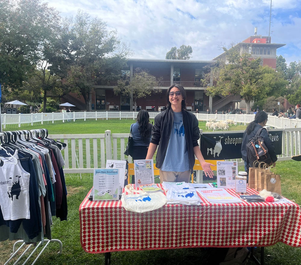 Student at table of merchandise in front of pasture 