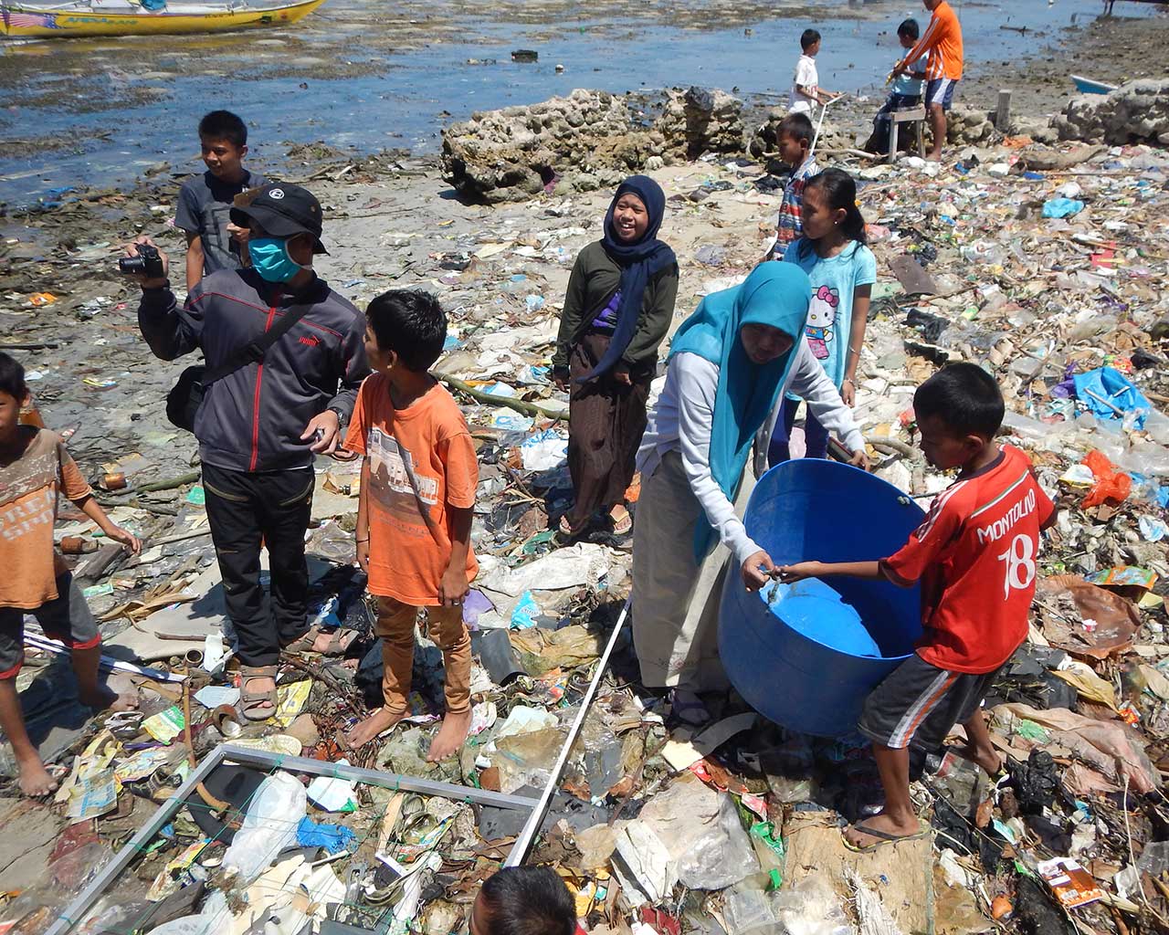 Photo of several people cleaning up a beach strewn with plastic debris.