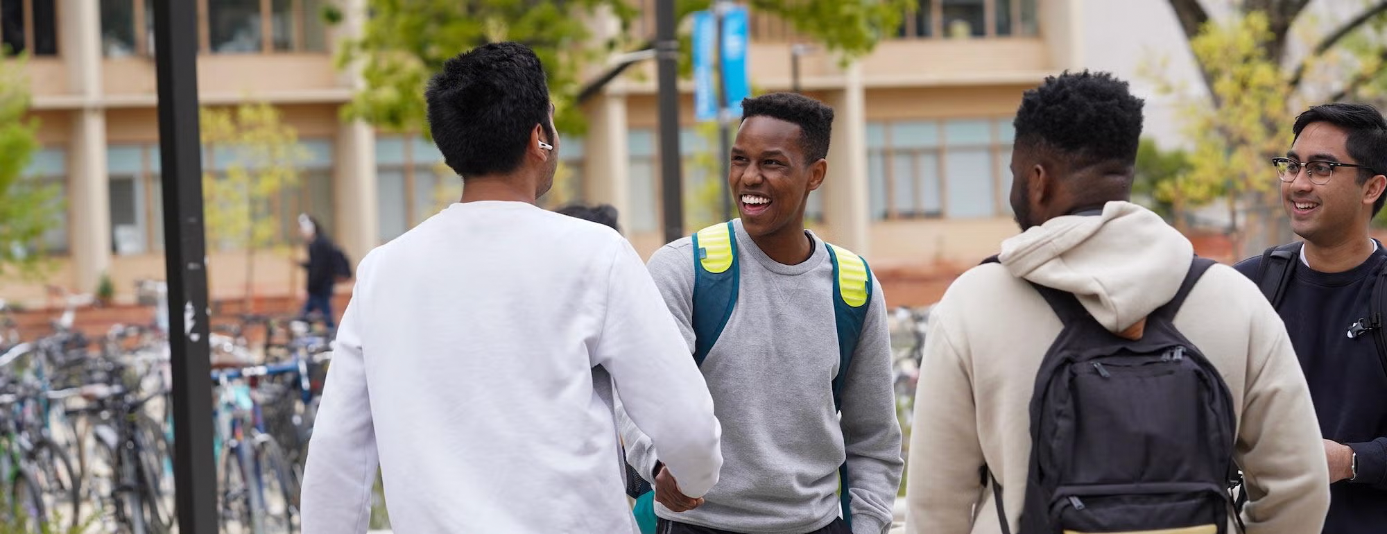 Several UC Davis students laugh in front of a building on campus