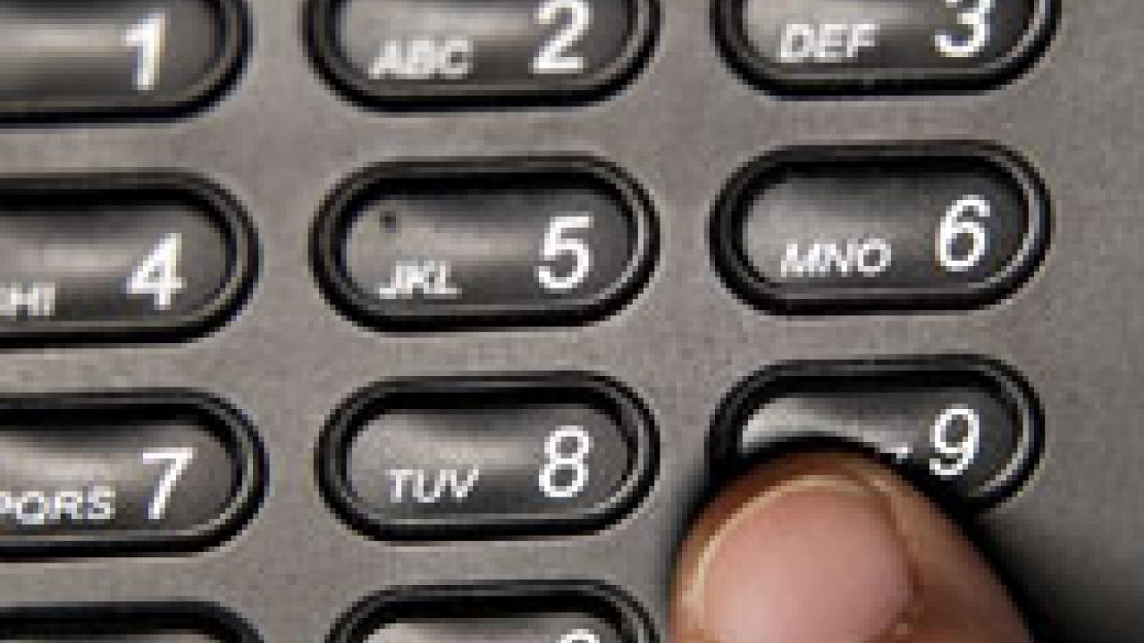 A finger on a telephone's 9 button