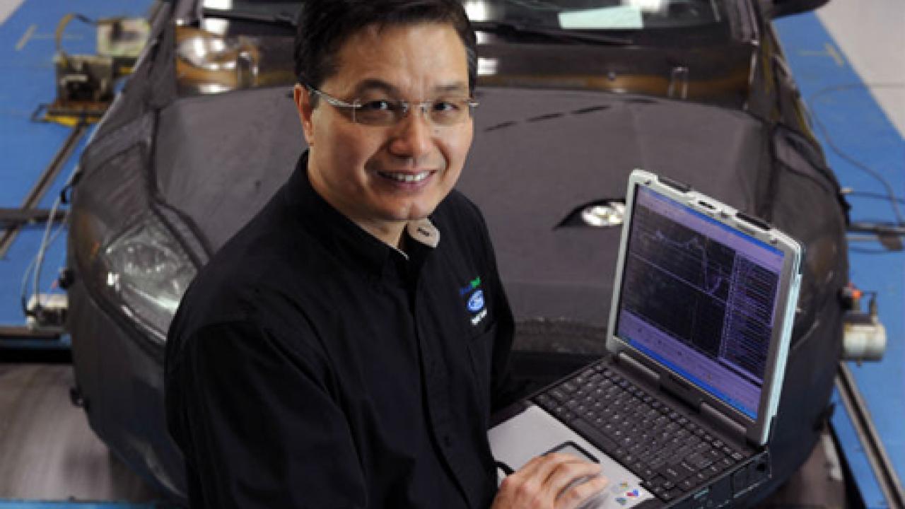 Photo: Ming Kuang with laptop computer and car