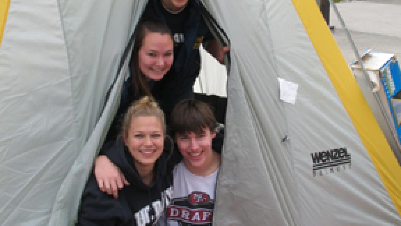 Students Chris Perry, Courtney King, Jamie Flynn and Adam Darbonne peek out of a tent outside the Pavilion.
