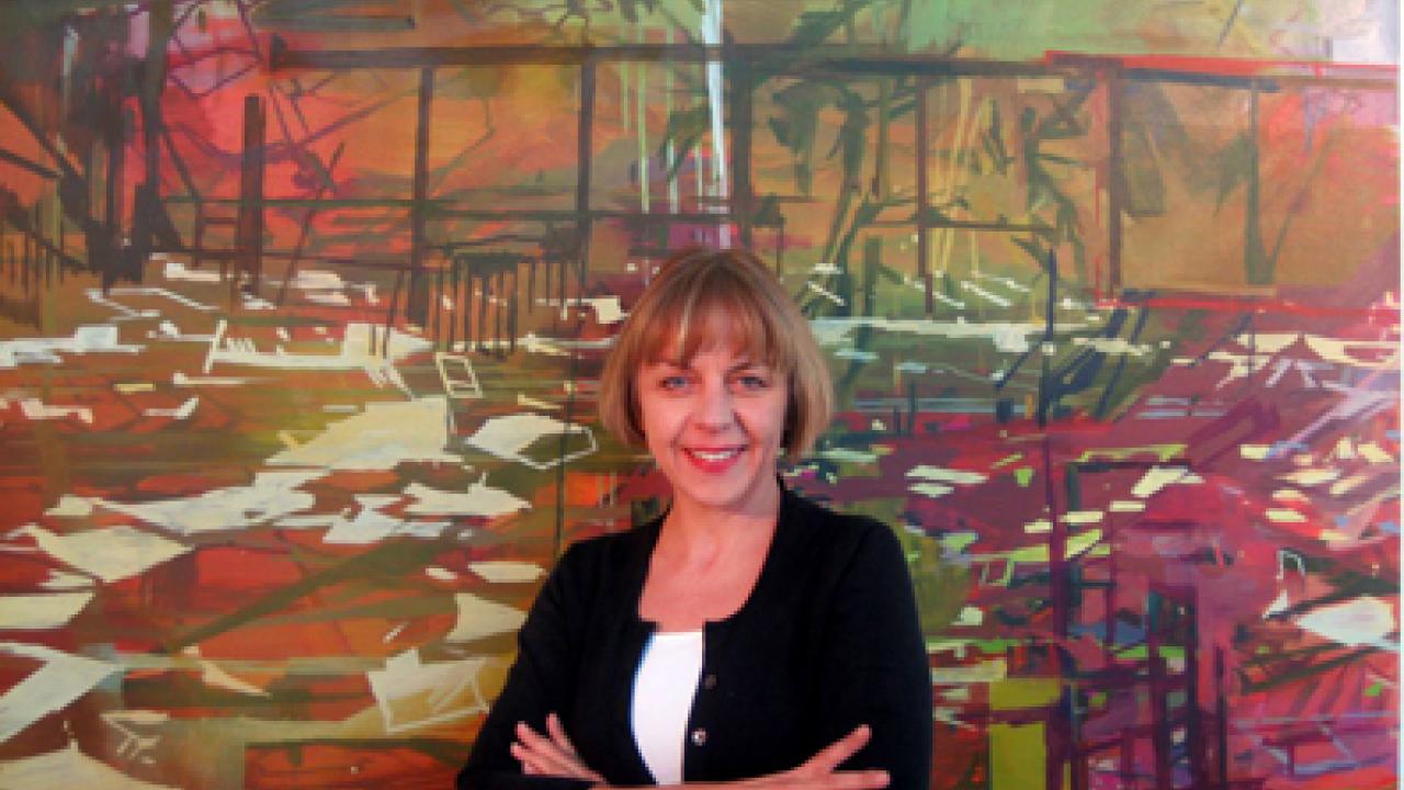 Marie Thibeault stands in front of Arena (oil on canvas, 71 by 77 inches), a 2007 work inspired by Hurricane Katrina