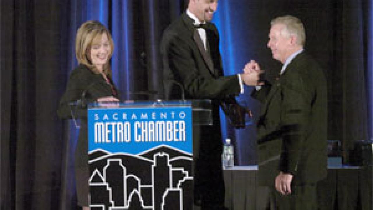 KCRA Channel 3 news anchor Diedre Fitzpatrick, left, looks on as Tom Stallard, right, shakes the hand of Sacramento Metro Chamber CEO Matt Mahood. Stallard, a longtime UC Davis alumni board member, accepted the chamber&rsquo;s Small Business of the 
