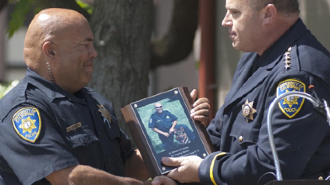 Photo: UC Davis police officer Walter Broussard receives a plaque from Police Chief Matt Carmichael, in memory of K-9 officer Grimm.