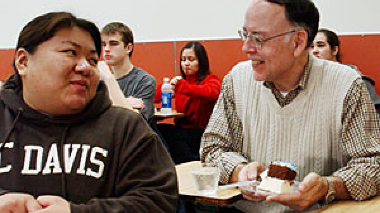 Photo: Female student turns to professor with piece of cake