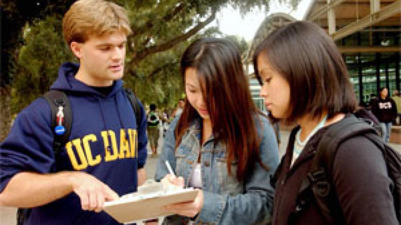 Brian McInnis, left, signs-up Edelyn Low, center, a fourth-year student, and her friend Julie Chiu, as he works to register prospective voters on  campus last week.
