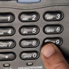 A finger on a telephone's 9 button