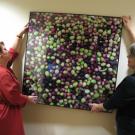 Sue Norris and Charlotte Delaire-Meyers of Student Affairs Design Services hang new artwork -- a photo of UC Davis olives -- in the Gunrock Pub.