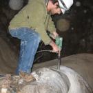 Neil Kelley, a doctoral student in geology, drills into a stalagmite at Moaning Cavern.