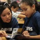 Alumna Julia Nguyen helps Oakland student Ana Melgoza through the Aggie Pride book. 