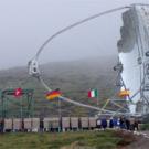 photo: big outdoor telescope with flags in foreground