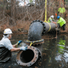 Utility Services workers installed the inlet pipe for the waterway improvement project late last year. Water foreman Mel Garcia is in the foreground. Pictured on either side of the pipe are Dwayne Straub, senior building maintenance worker, left