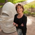 Woman poses with "Eye on Mrak" Egghead sculpture.