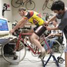 Maury Hull spins the pedals on his Computrainer while doctoral candidate Matt Camilleri affixes a third reflective globe that will help wall-mounted sensors create a 3-dimensional map of the rider&rsquo;s movements while cycling. The Computrainer si