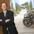 Photo: Vice Chancellor John Meyer, leaning against a building, with bicycle rack in background