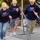 Photo: Woman and two men in hard hats carry bridge parts on the run