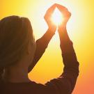 Woman cupping hands around the sun's image