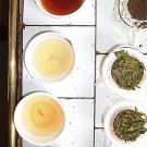 Photo of various cups of tea with dried tea leaf samplings on the side 