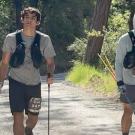 Ultramarathoners walk with poles in wooded area