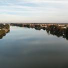 A view up a broad river with a small town on the right bank. 