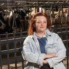 Caroline Williams stands in front of dairy cows at a trough.