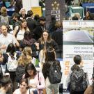 Many students crowd around employers and their banners at a career fair