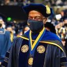 In full academic regalia, Chancellor Gary S. May strides through graduates