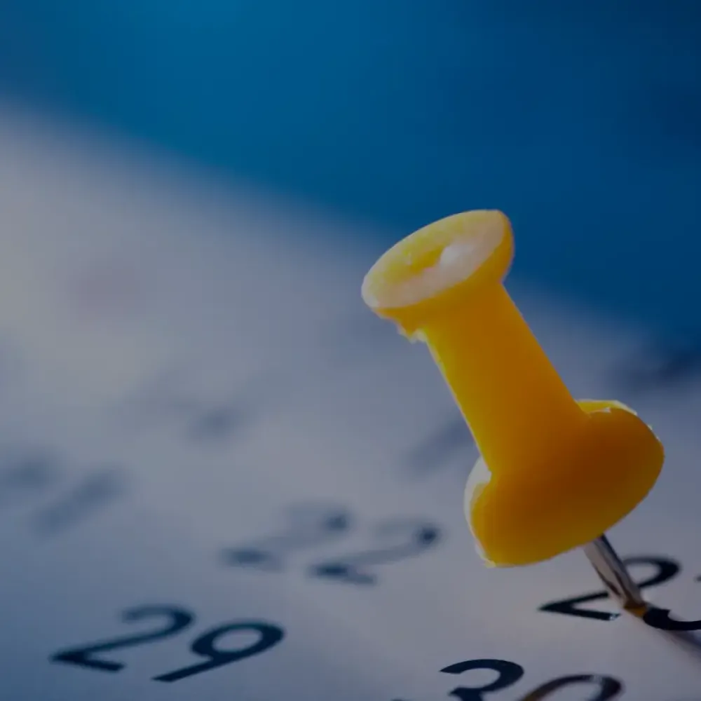 a close-up of a yellow push pin in a calendar